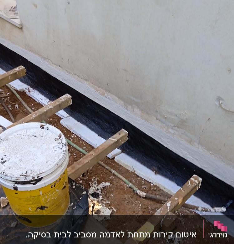 קיר אטום עם חומר איטום שחור ודלי צהוב